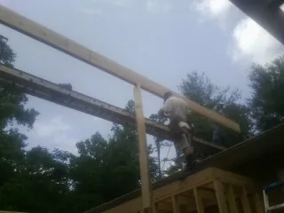 Carpenter setting a ridge beam over a new addition frame — Ice Dam Removal by Roofing Brothers in Port Henry