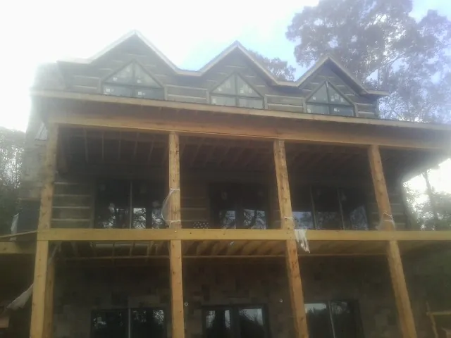 Dormers and porch framing on a large log home under construction — Roof Coating work by our crew in Port Henry