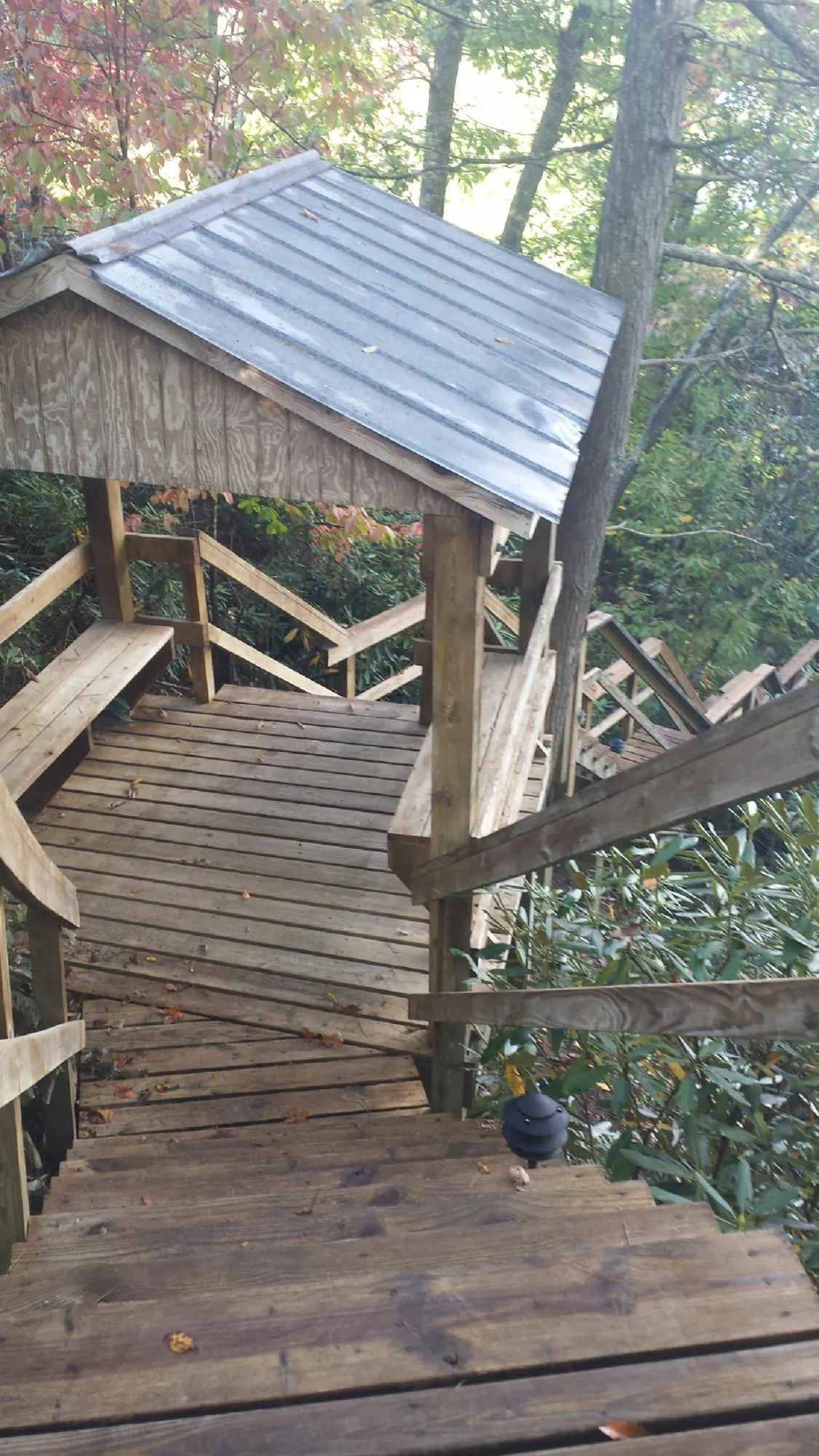 Metal roofed shelter over wooden steps on a wooded walkway — Skylight Repair & Installation work by our crew in Port Henry