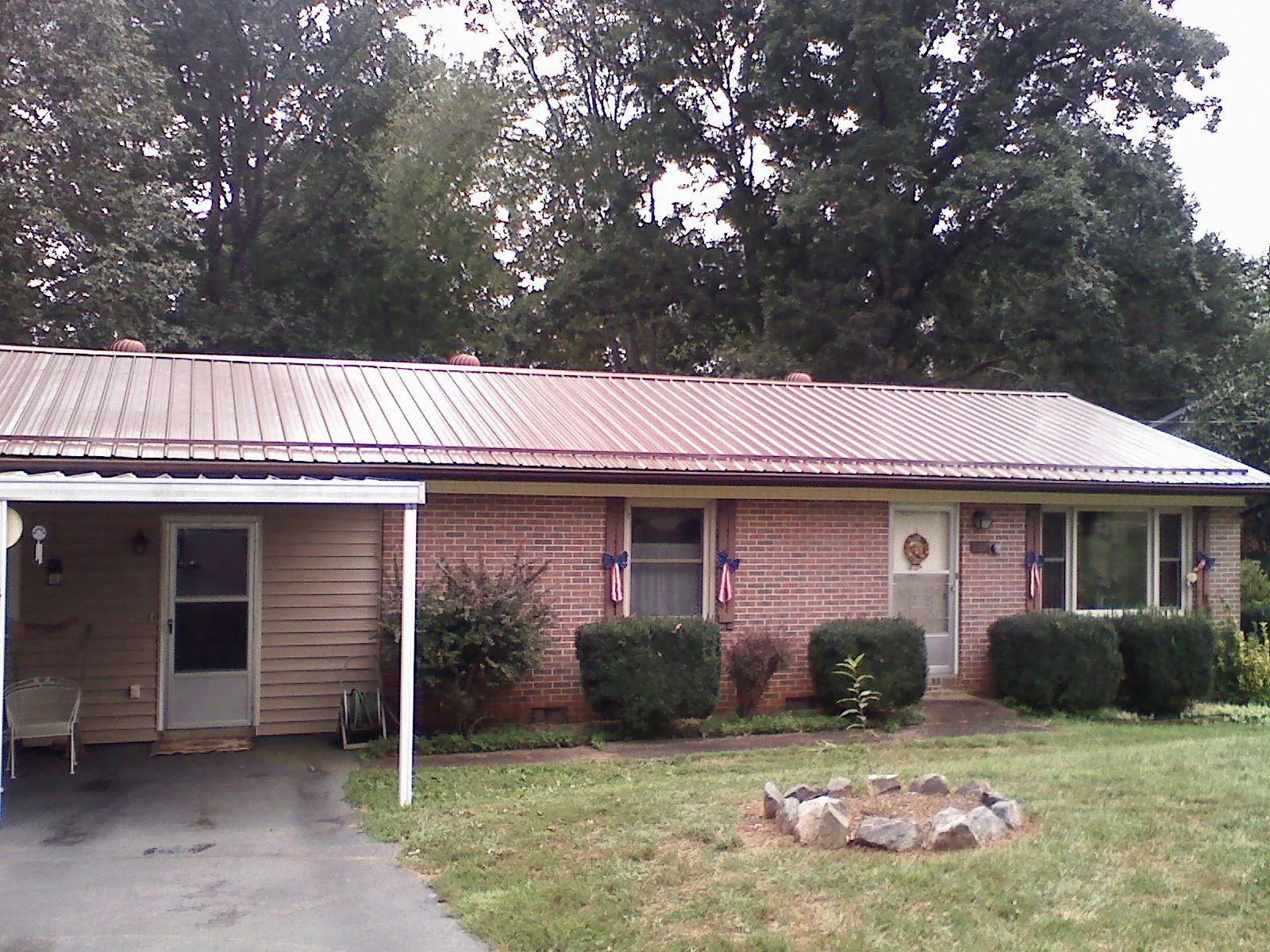 Bronze metal roof and carport on a brick ranch home — Roof Repair work by our crew in Port Henry